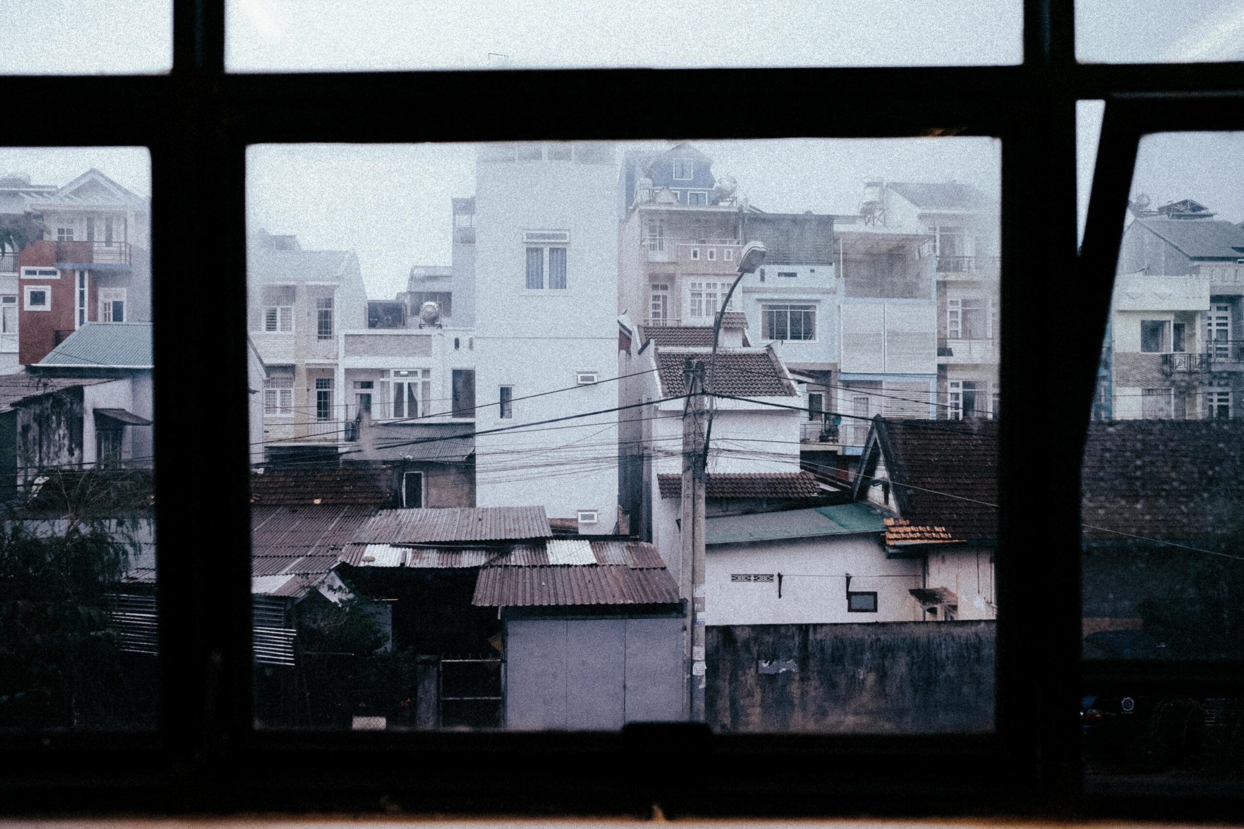 View of urban residential buildings through a misty window, creating a serene and moody atmosphere.